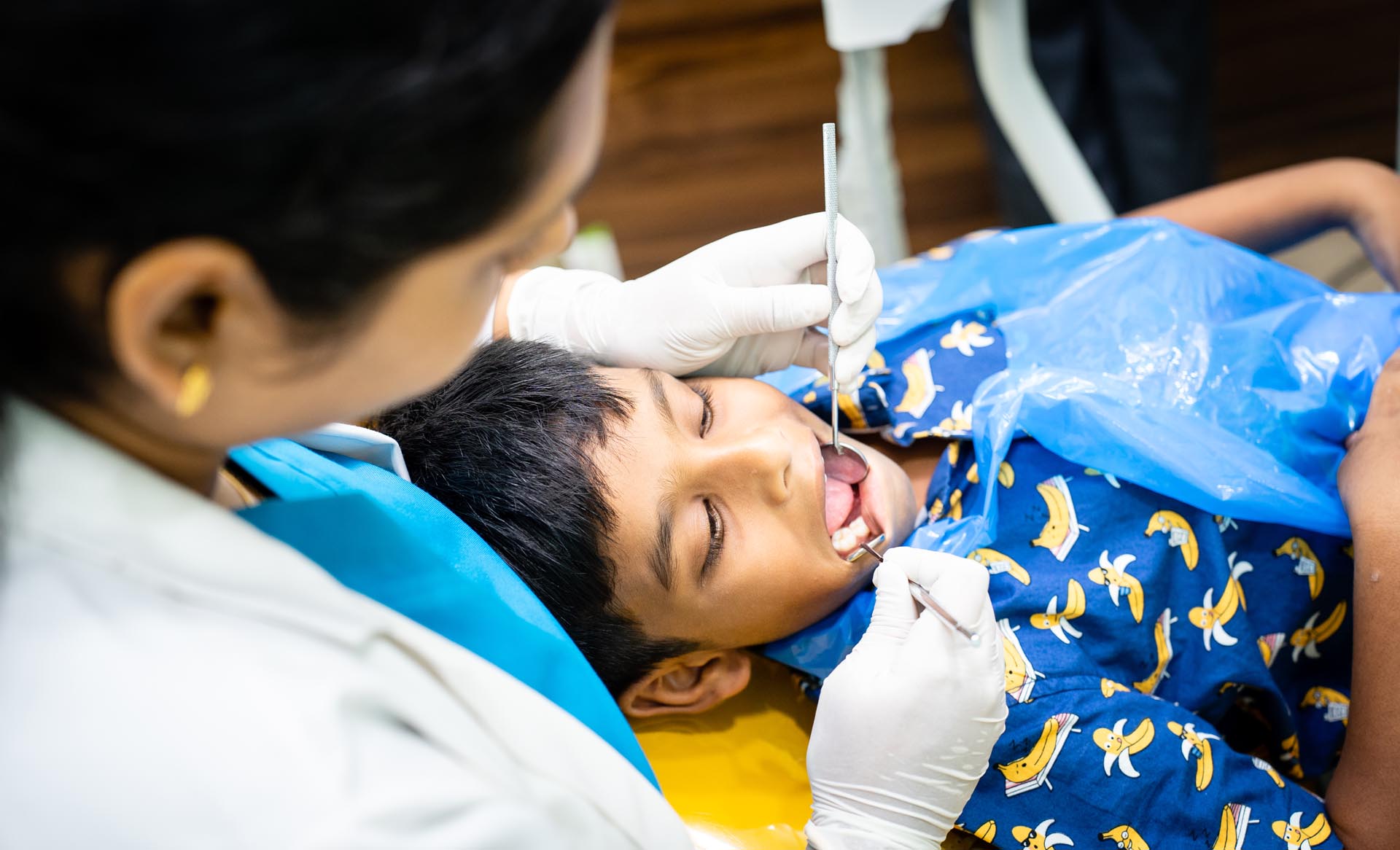 Dr.Sangeeta teleti checking kids teeth with dental tools & the kid is lying on the dental chair