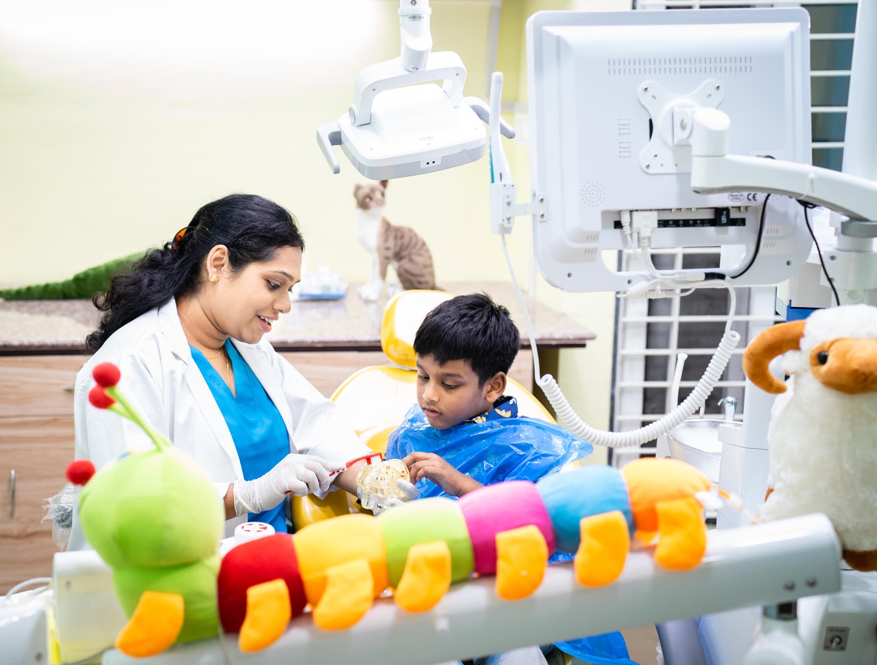 Pediatric dentist Dr.Sangeeta demonstrating proper tooth brushing techniques to a young child.