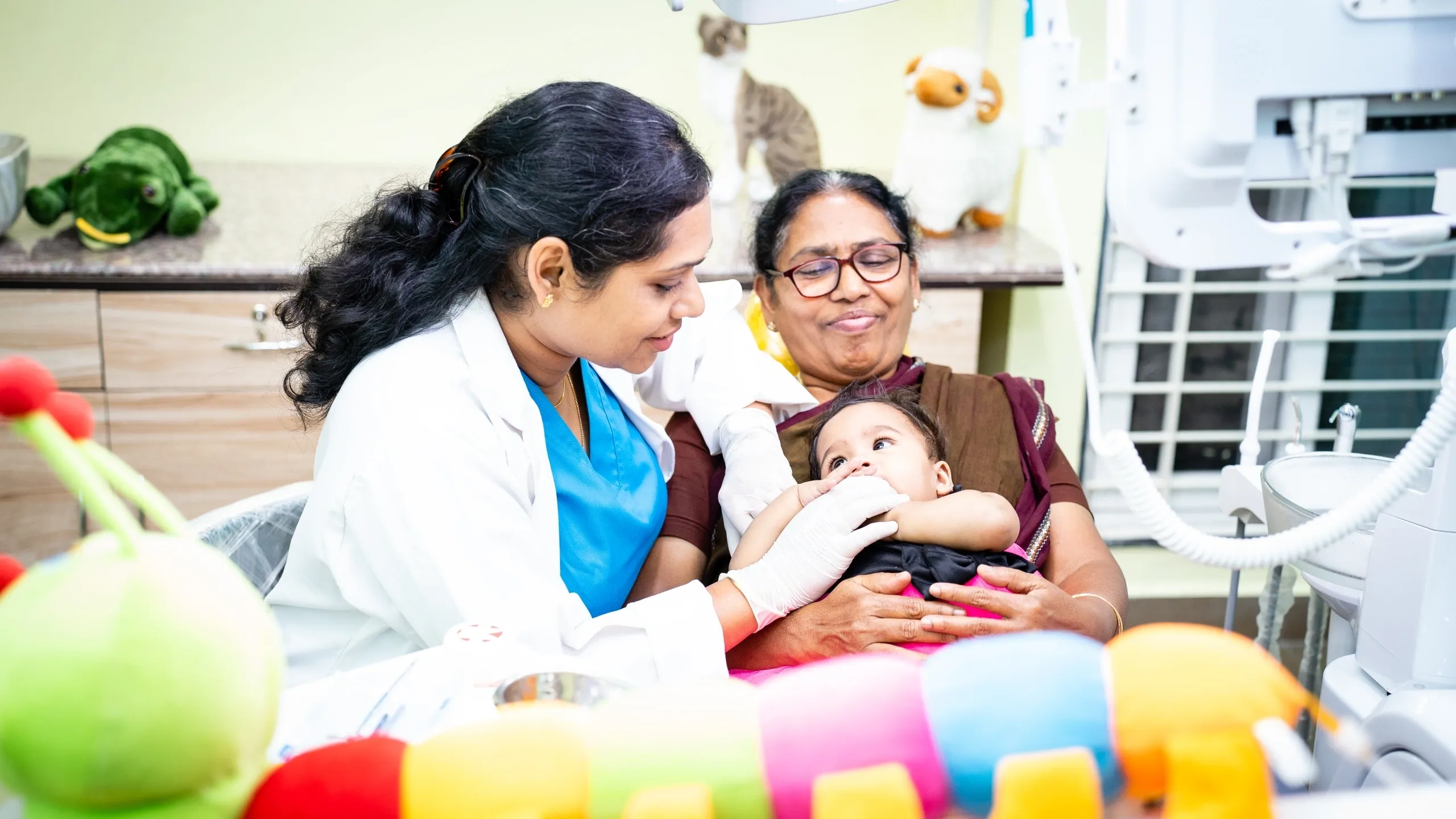 Dr.Sangeeta examining an infant girl's tooth by hand.