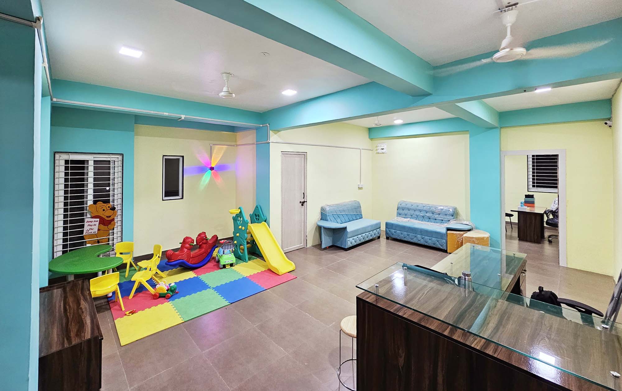 Interior of the pediatric dental clinic featuring a reception table, a play area with toys, and a waiting area for patients.